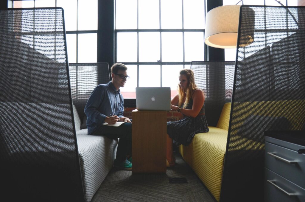 Two people sitting on a couch with laptops