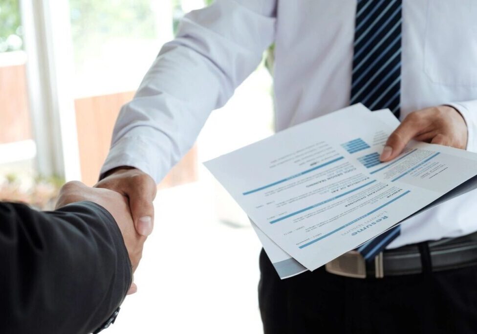 qtq80-bpIB8w Two people shaking hands over a document.